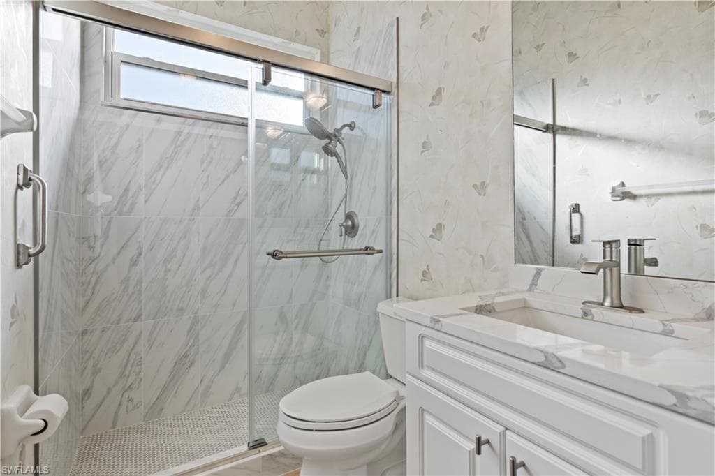 Bathroom featuring vanity and a marble finish shower