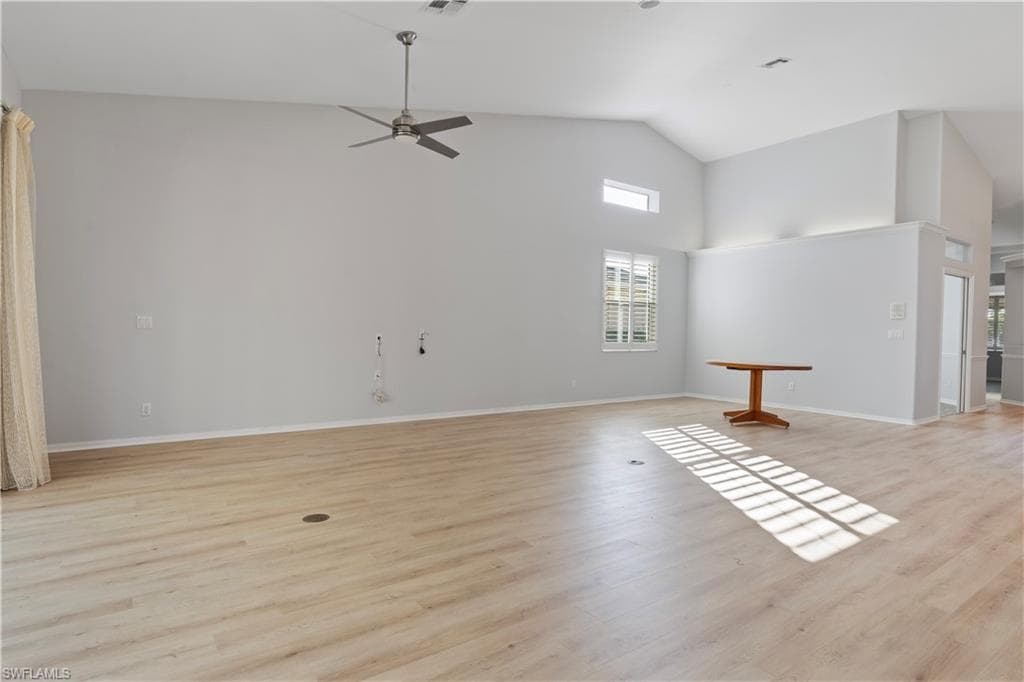 Unfurnished living room with a ceiling fan, light wood finished floors, and high vaulted ceiling