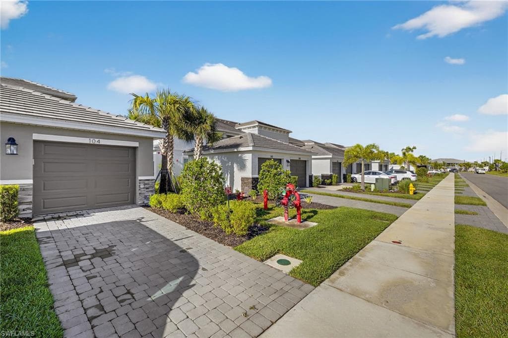 View of front of home featuring a residential view, stucco siding, decorative driveway, and stone siding