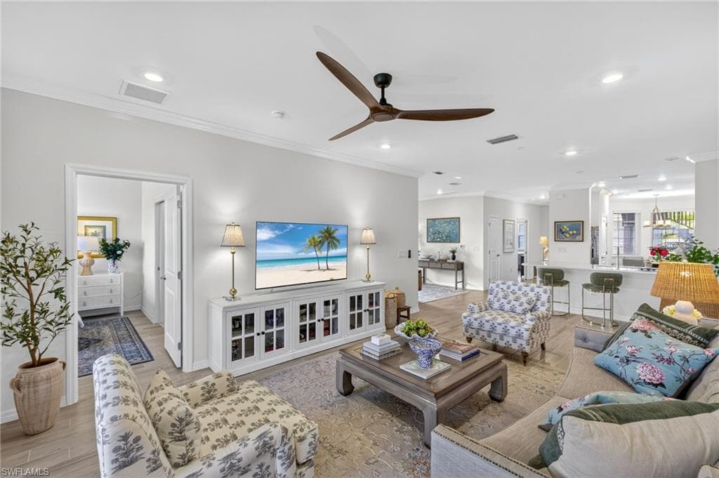 Living room with light wood finished floors, ornamental molding, a ceiling fan, and recessed lighting