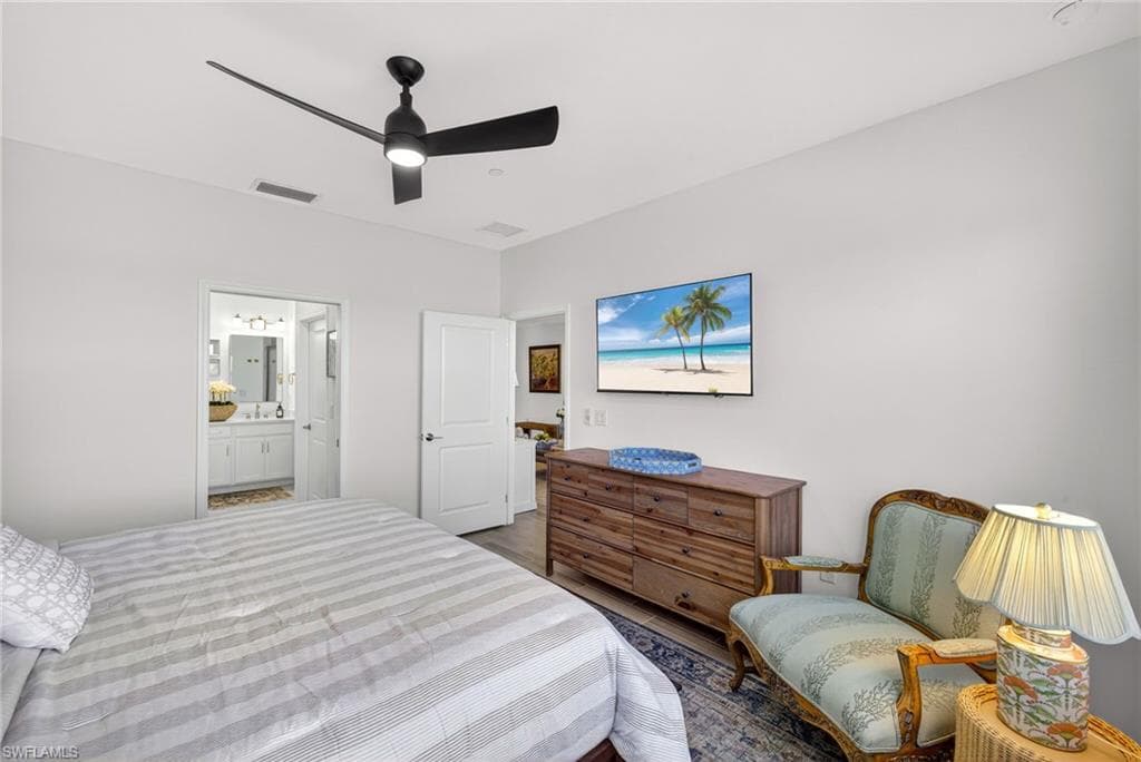 Bedroom with ceiling fan, dark wood-type flooring, and ensuite bathroom