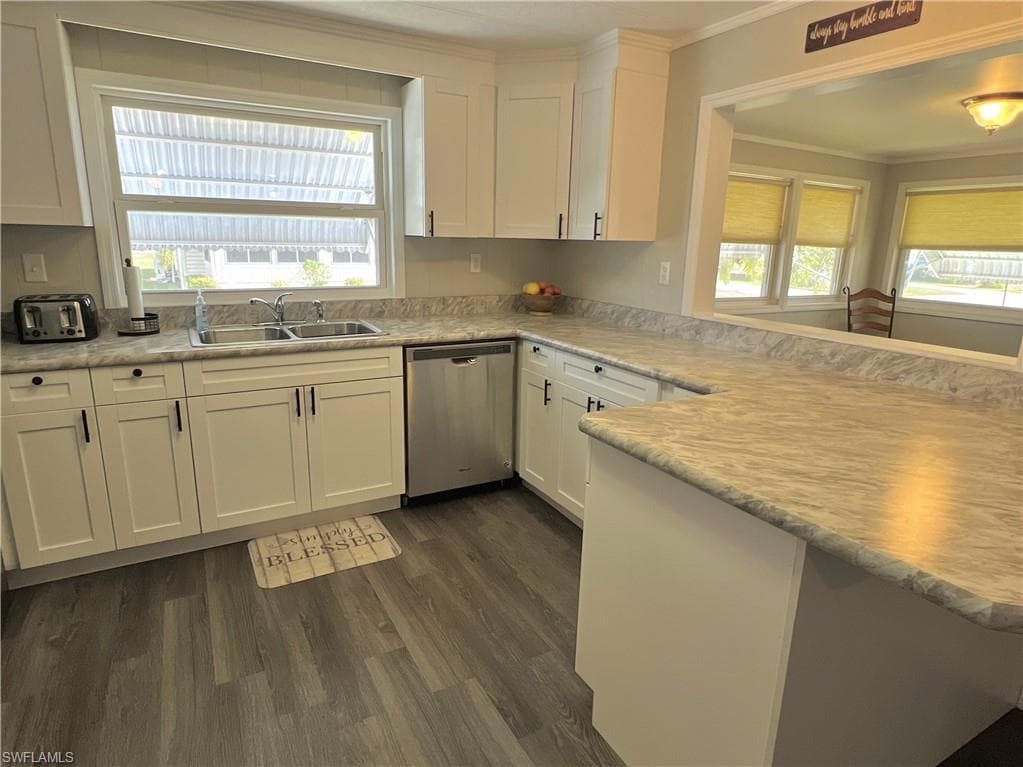Kitchen with white cabinetry, light countertops, dishwasher, dark wood-type flooring, and a peninsula with space for 2 bar stools.