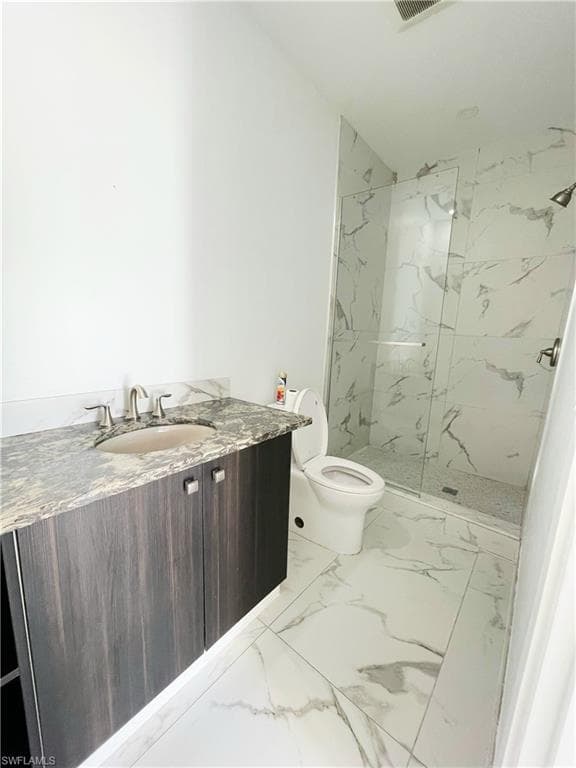Bathroom featuring vanity, a marble finish shower, and light marble finish floors