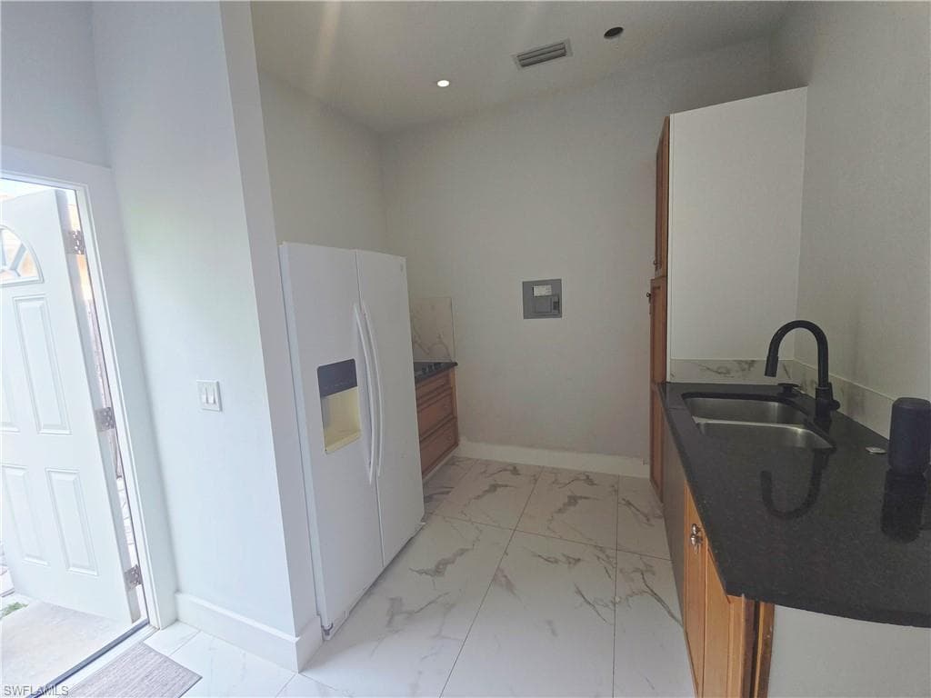 Mother-in-law Kitchen featuring white refrigerator with ice dispenser, dark stone counters, and light marble finish floors