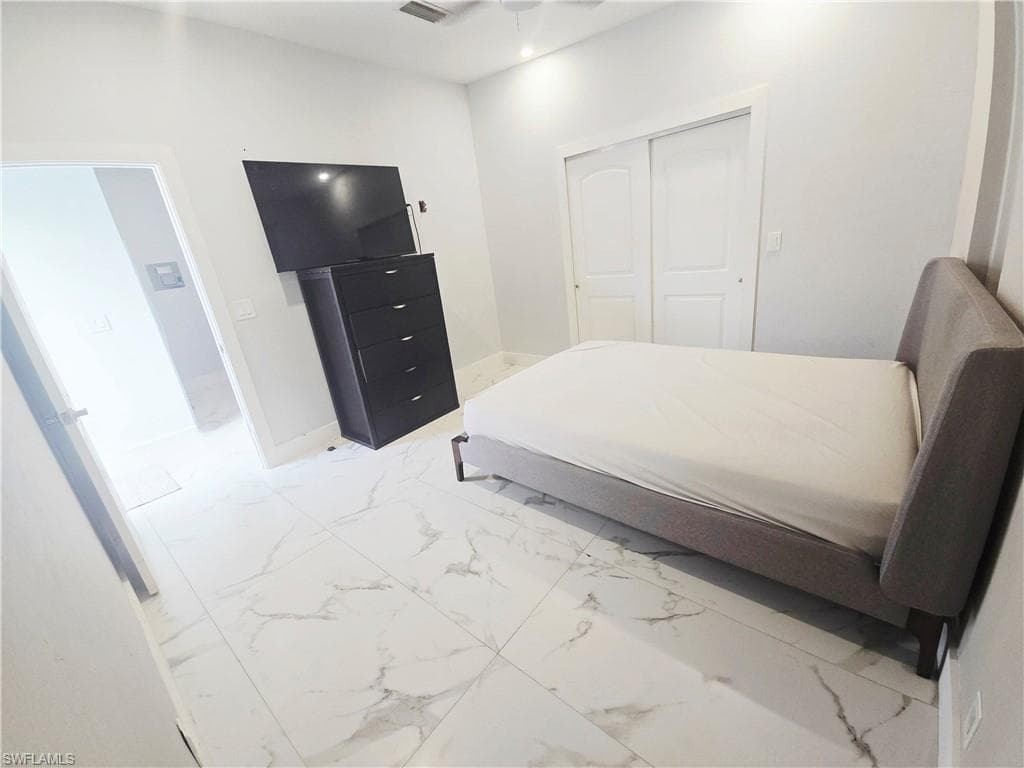 Mother-in-law Bedroom featuring light marble finish floors and a closet