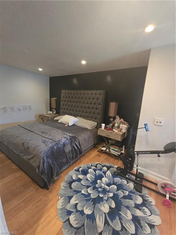 Bedroom with a textured ceiling, wood finished floors, and recessed lighting