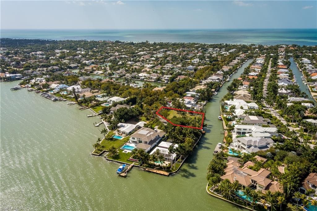 Aerial view of residential area with a large body of water and property boundaries highlighted