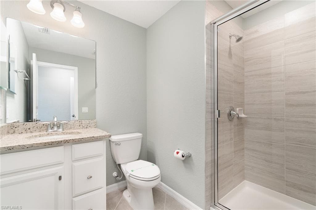 Bathroom featuring vanity, a shower stall, and light tile patterned floors