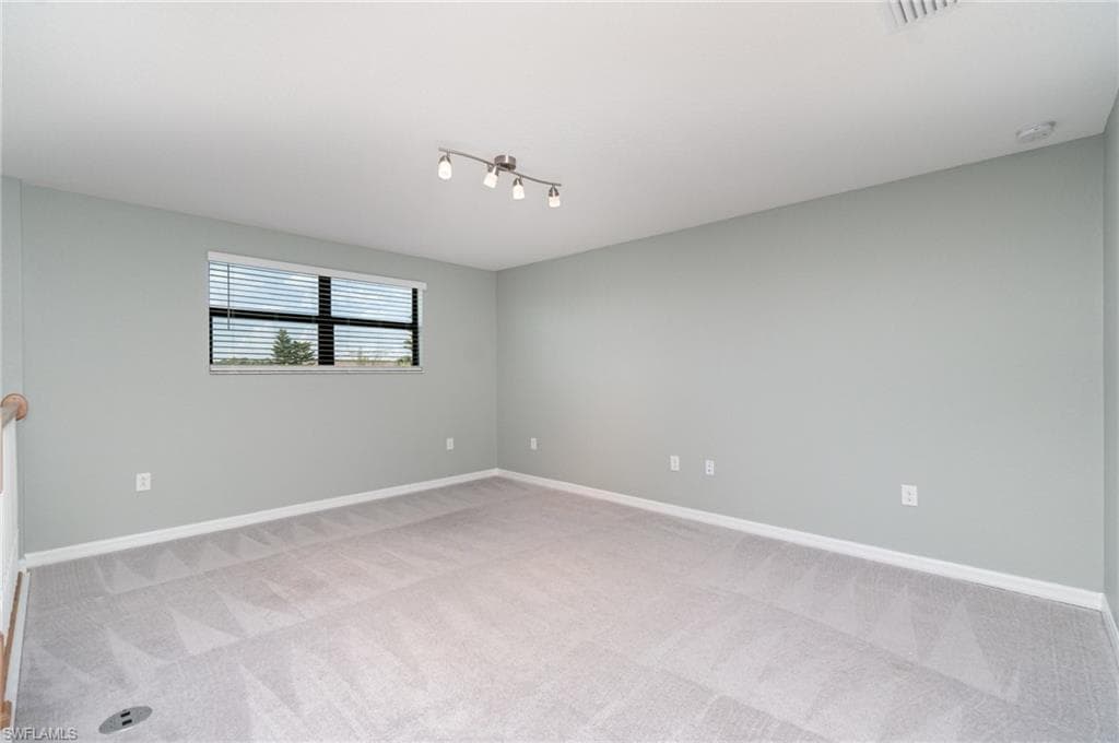 Unfurnished room with light colored carpet and baseboards