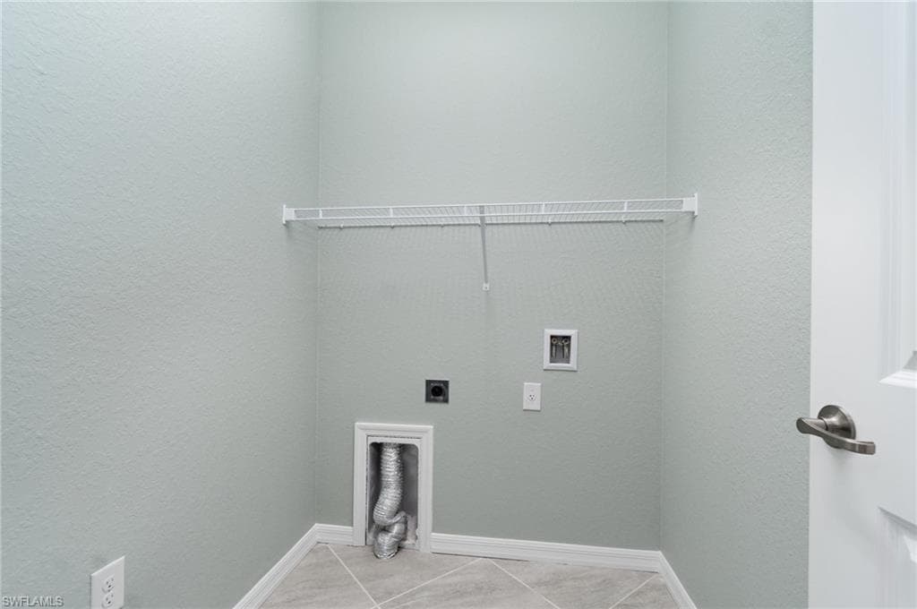 Laundry room with hookup for an electric dryer, tile patterned floors, washer hookup, and a textured wall