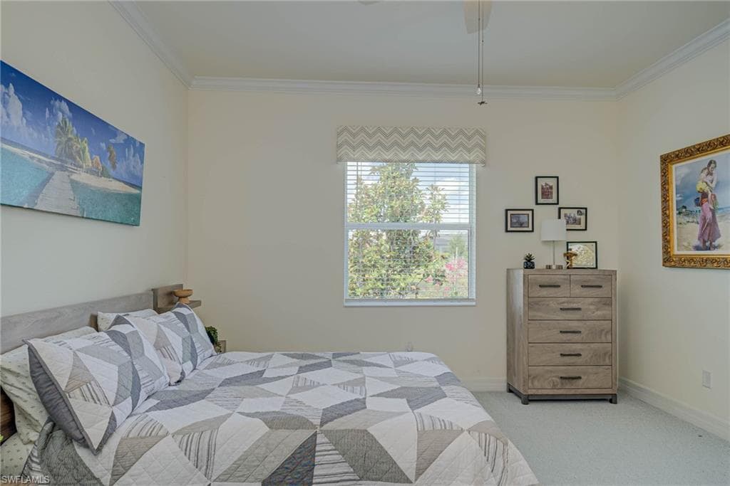 Carpeted bedroom featuring crown molding and baseboards