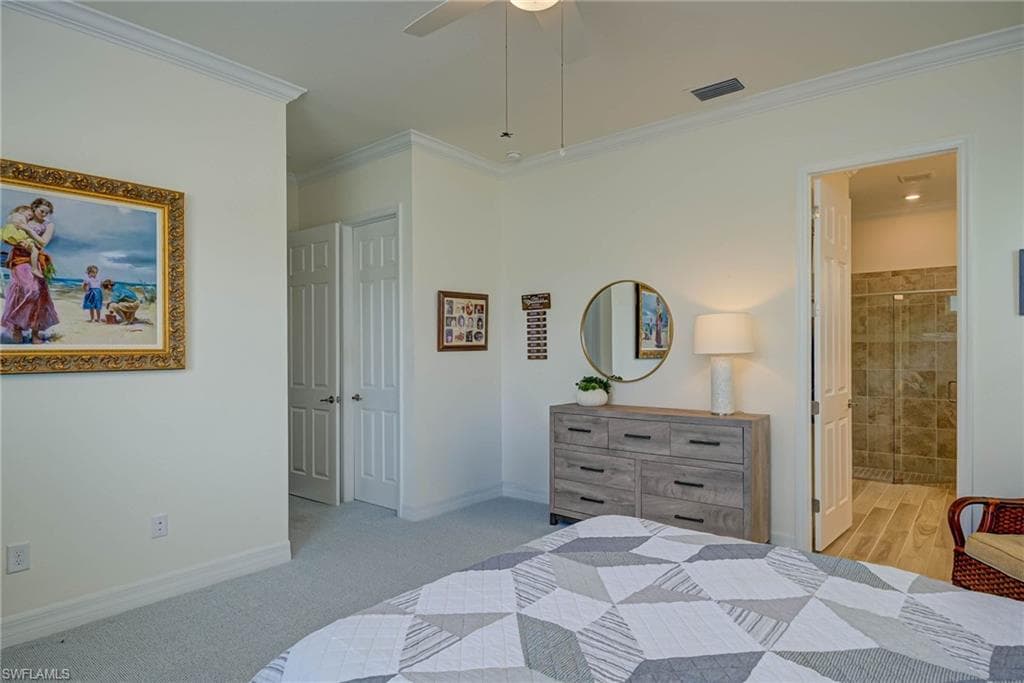 Bedroom featuring ornamental molding, ensuite bathroom, ceiling fan, and light carpet