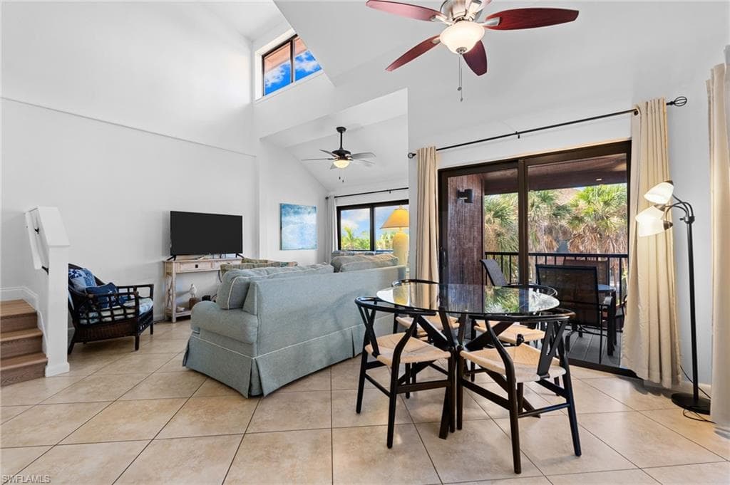 Living room with a high ceiling, ceiling fan, light tile patterned floors, and stairs