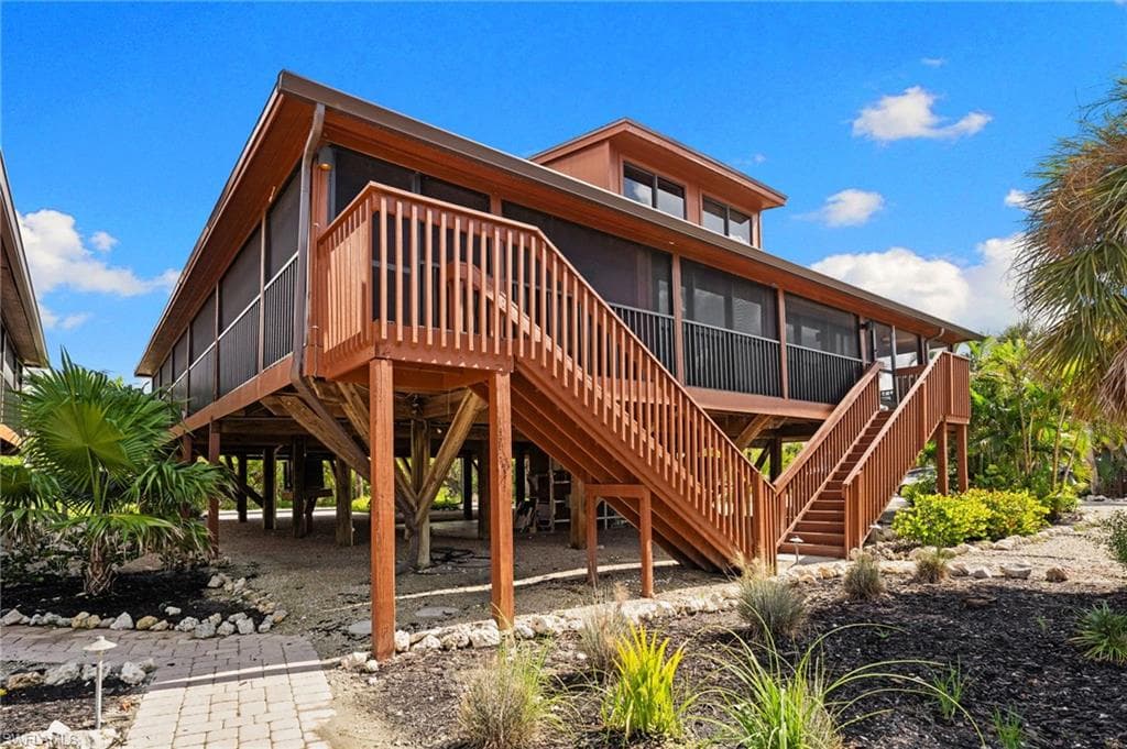 Rear view of property with a sunroom and stairway