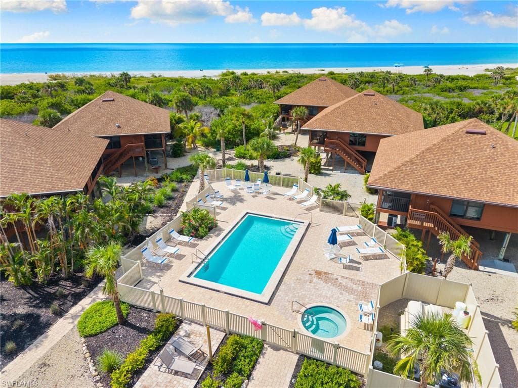 Community pool featuring a patio, view of water and beach, and stairway