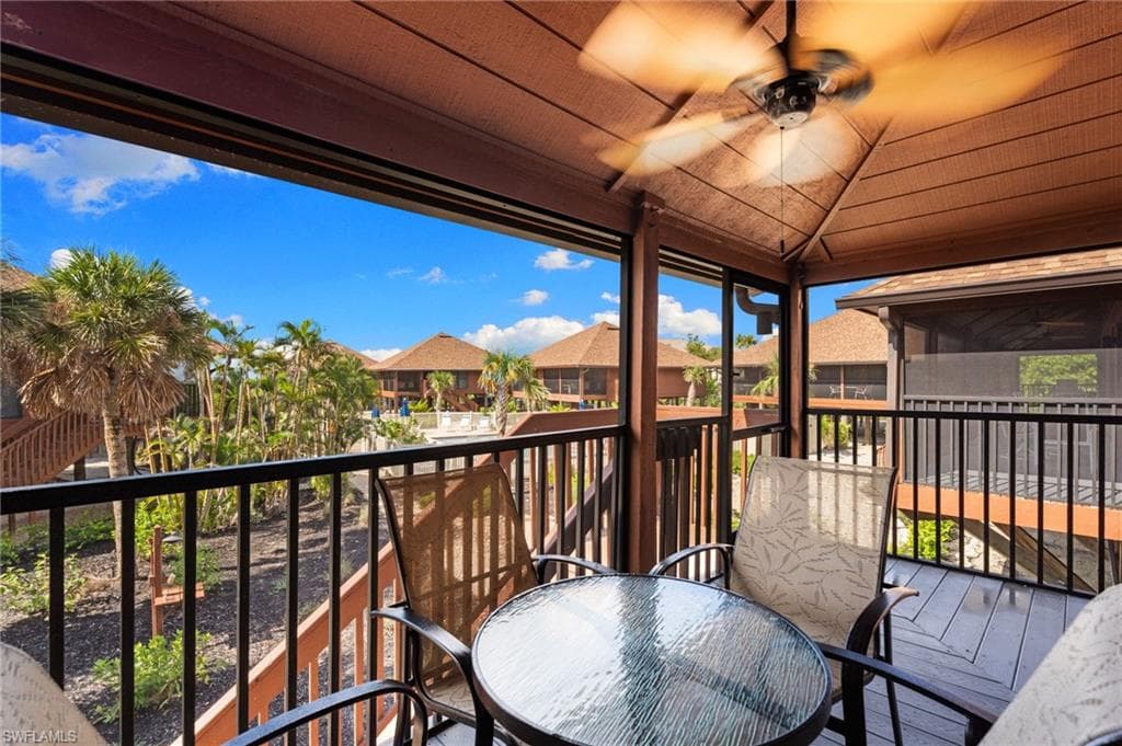 Balcony with a sunroom, a residential view, a ceiling fan, and outdoor dining space