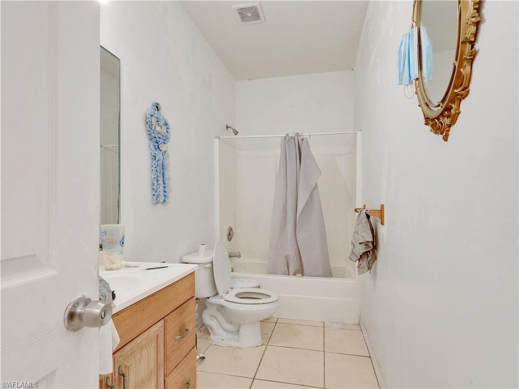 Full bathroom with shower / bath combo, light tile patterned floors, and vanity