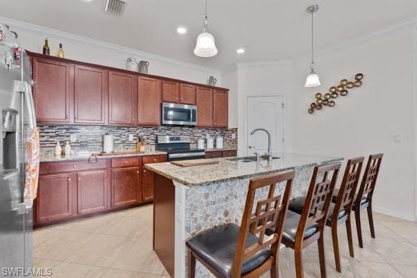 Kitchen featuring tasteful backsplash, light stone counters, appliances with stainless steel finishes, light tile patterned floors, and crown molding