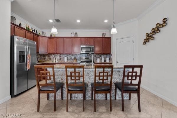 Kitchen featuring appliances with stainless steel finishes, a breakfast bar area, decorative backsplash, decorative light fixtures, and crown molding