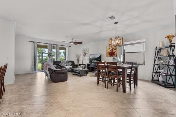 Dining room with crown molding, a ceiling fan, a chandelier, and light tile patterned floors