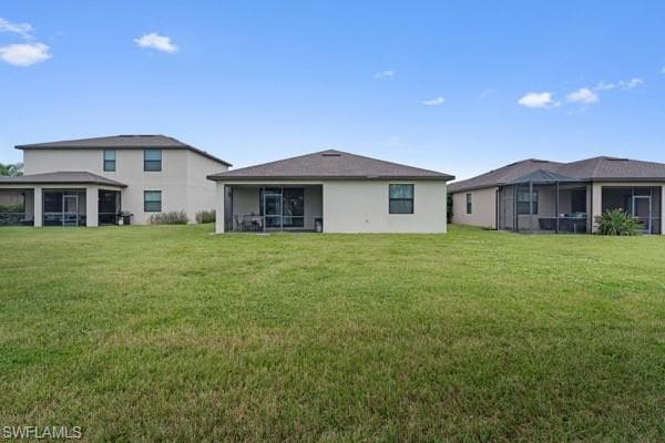 Back of property featuring a sunroom and a yard