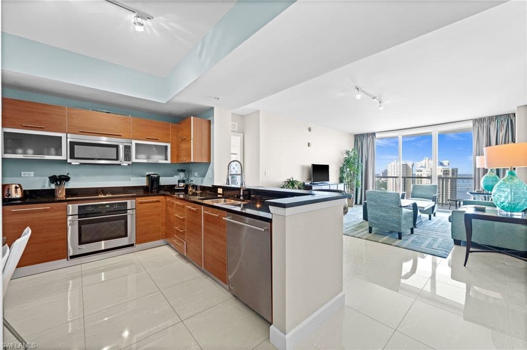 Kitchen featuring rail lighting, modern cabinets, light tile patterned floors, and floor to ceiling windows