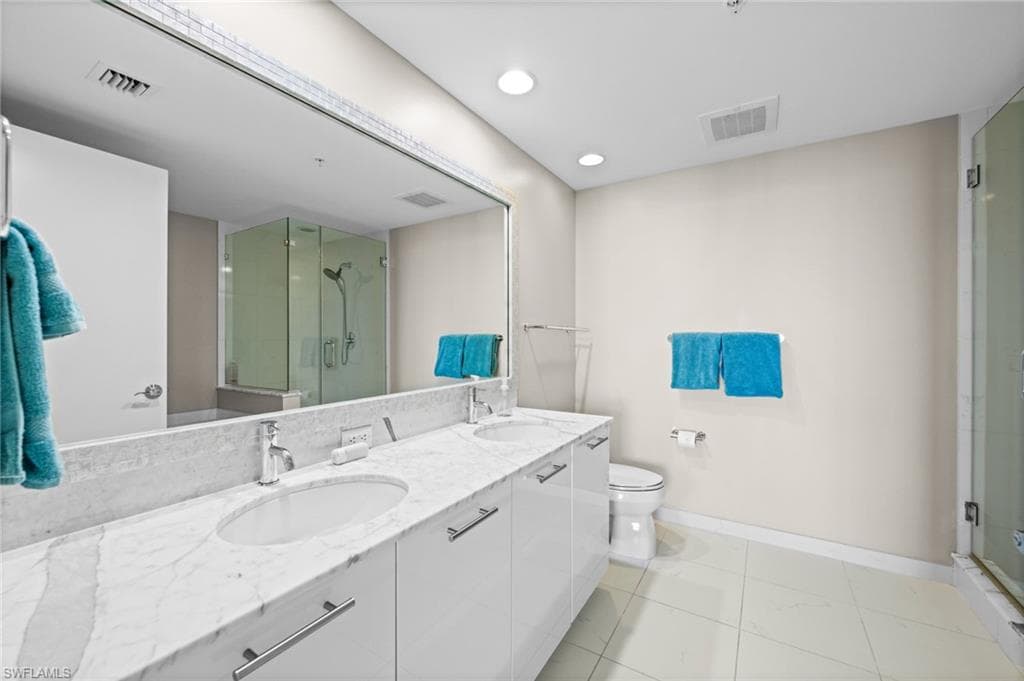 Full bathroom with double vanity, a stall shower, and recessed lighting