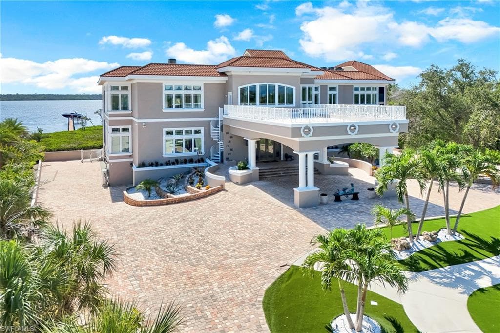 Back of house featuring a patio, a water view, a carport, stucco siding, and a tiled roof