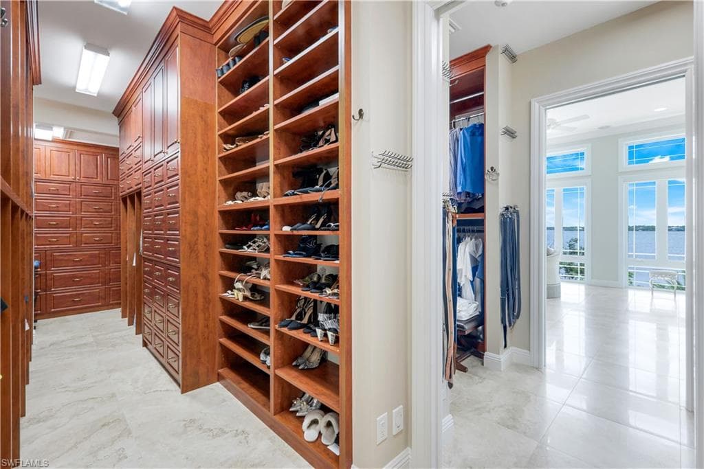 Primary closet featuring light tile patterned floors and baseboards