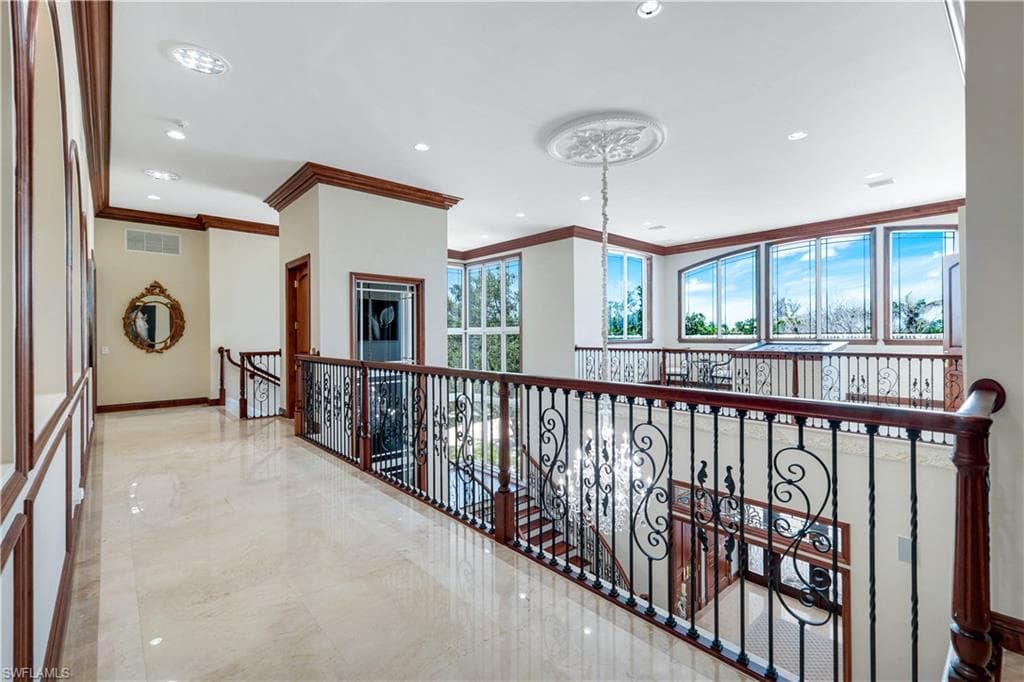 Hall with ornamental molding, recessed lighting, marble tiled floors, a chandelier, and an upstairs landing