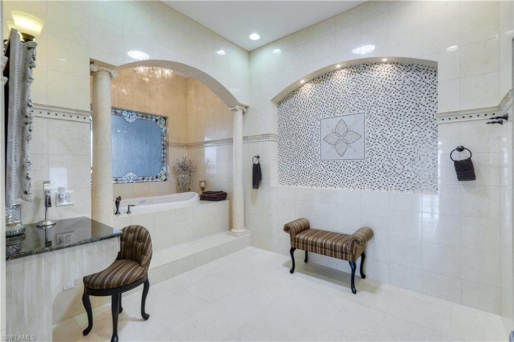 Bathroom with tile walls, a bath, tile patterned flooring, a chandelier, and recessed lighting