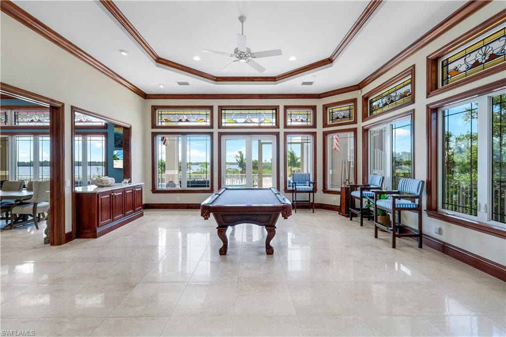 Rec room featuring pool table, crown molding, a tray ceiling, plenty of natural light, and a high ceiling