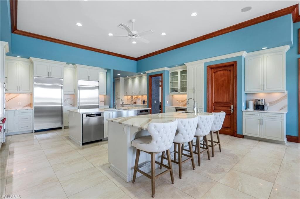 Kitchen featuring tasteful backsplash, ornamental molding, appliances with stainless steel finishes, a breakfast bar area, and recessed lighting