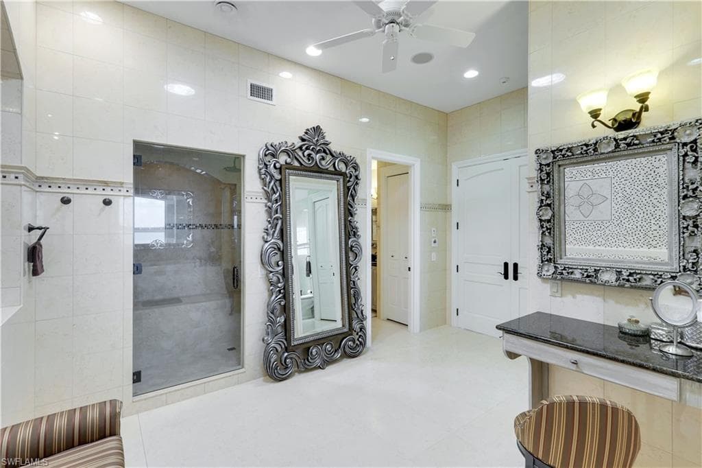 primary bathroom with a shower stall, tile walls, ceiling fan, recessed lighting, and vanity