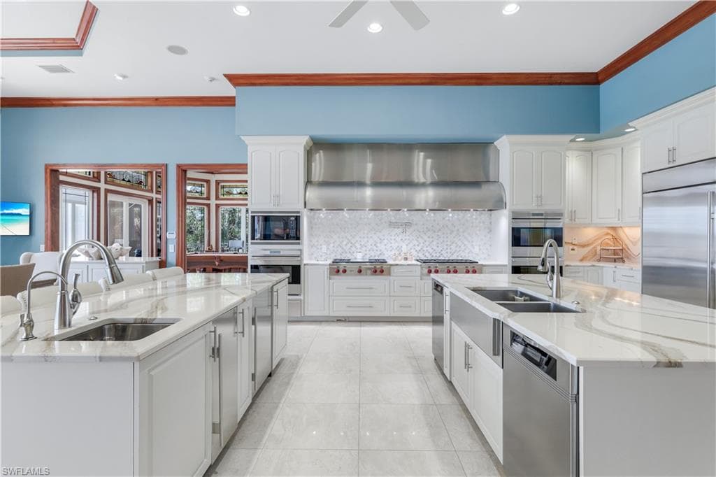 Kitchen with a kitchen island with sink, ornamental molding, light stone counters, tasteful backsplash, and recessed lighting
