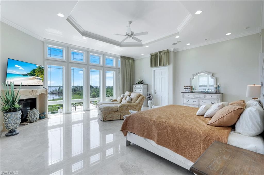 Bedroom with a raised ceiling, ornamental molding, a fireplace, ceiling fan, and recessed lighting