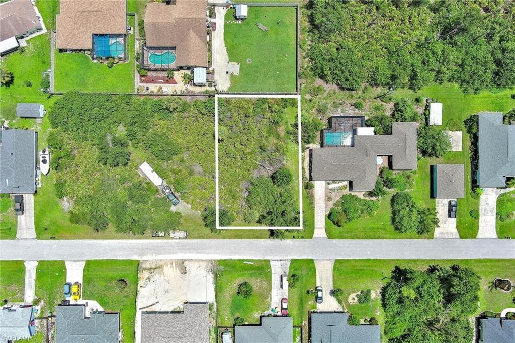 Aerial view of residential area with property parcel outlined and a pool area