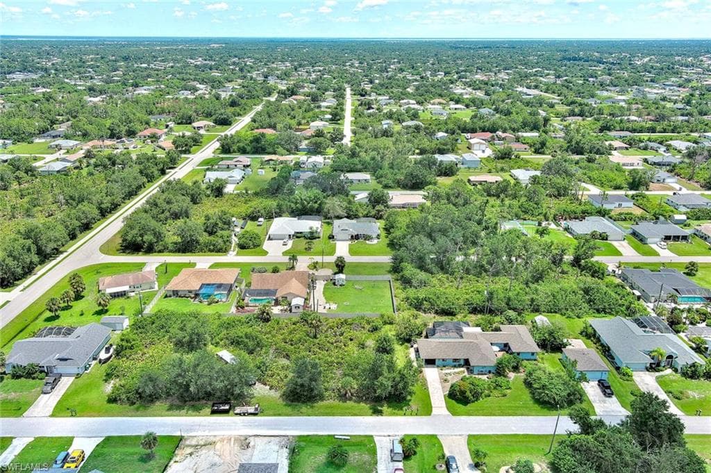 Aerial overview of property's location featuring nearby suburban area and a tree filled landscape