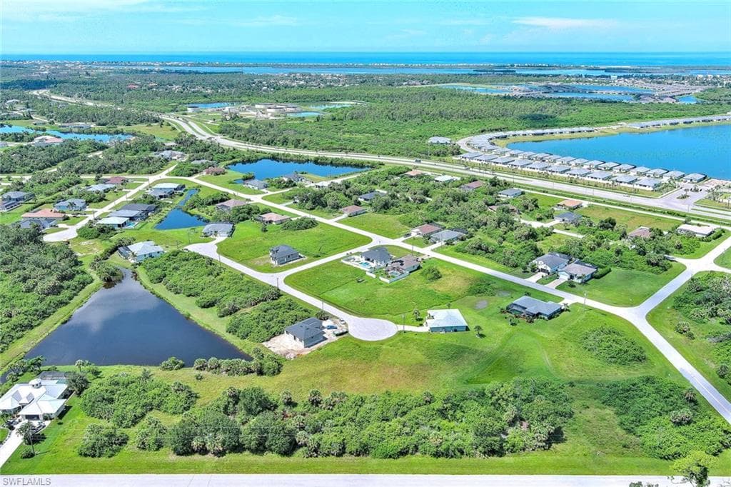 Aerial view of property's location featuring a large body of water and a tree filled landscape