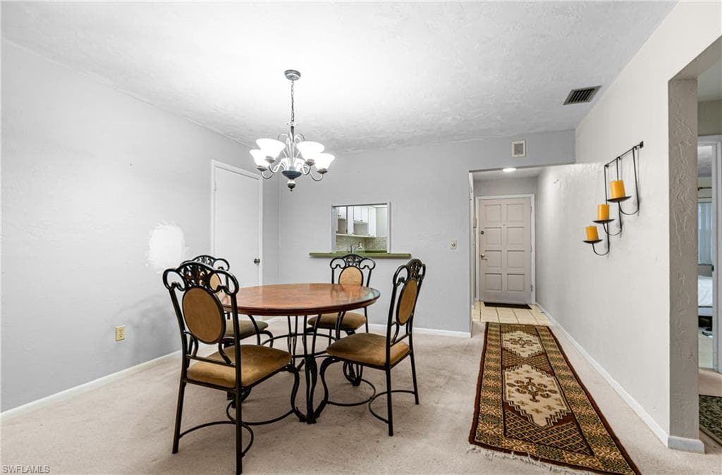Dining room featuring light carpet and a chandelier