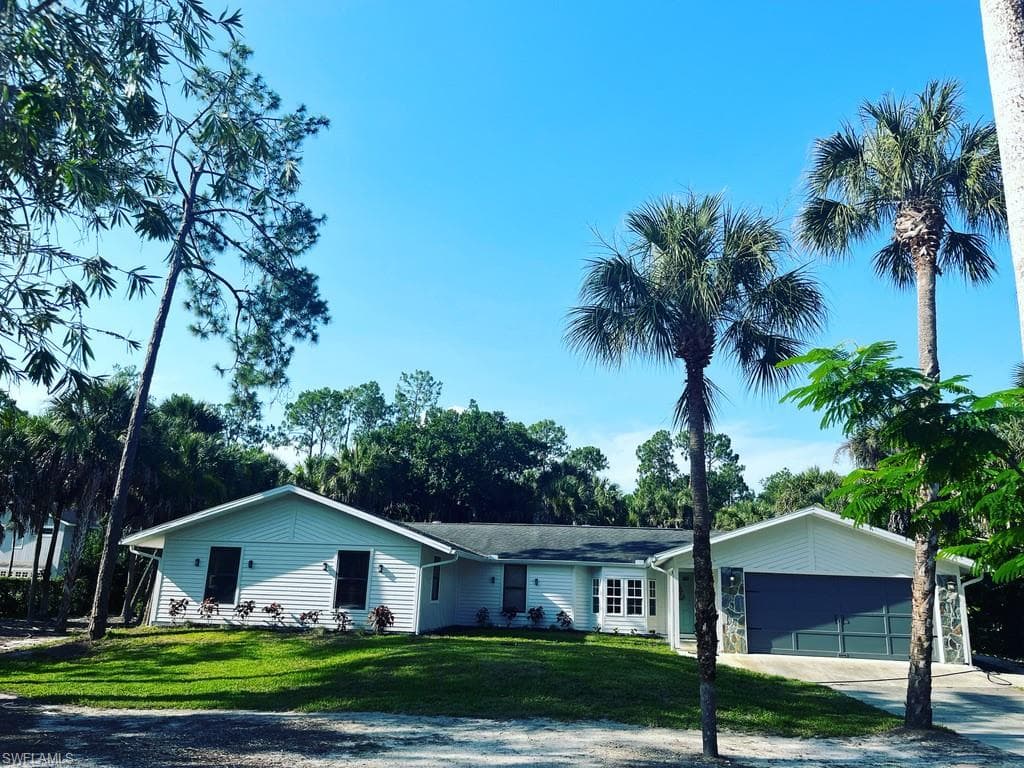 Ranch-style home featuring a front lawn, concrete driveway, and a garage