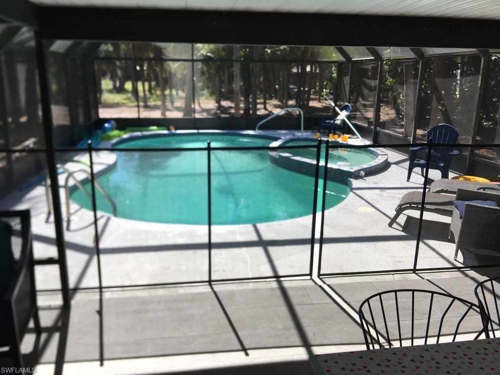 View of swimming pool with a sunroom, a pool with connected hot tub, a lanai, and a patio area