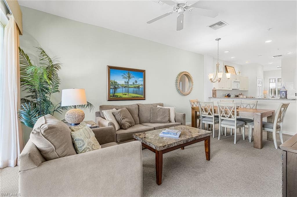 Living room with light carpet, recessed lighting, a ceiling fan, and a chandelier