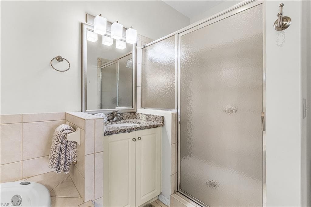 Full bathroom with vanity, a shower stall, a bath, and tile walls