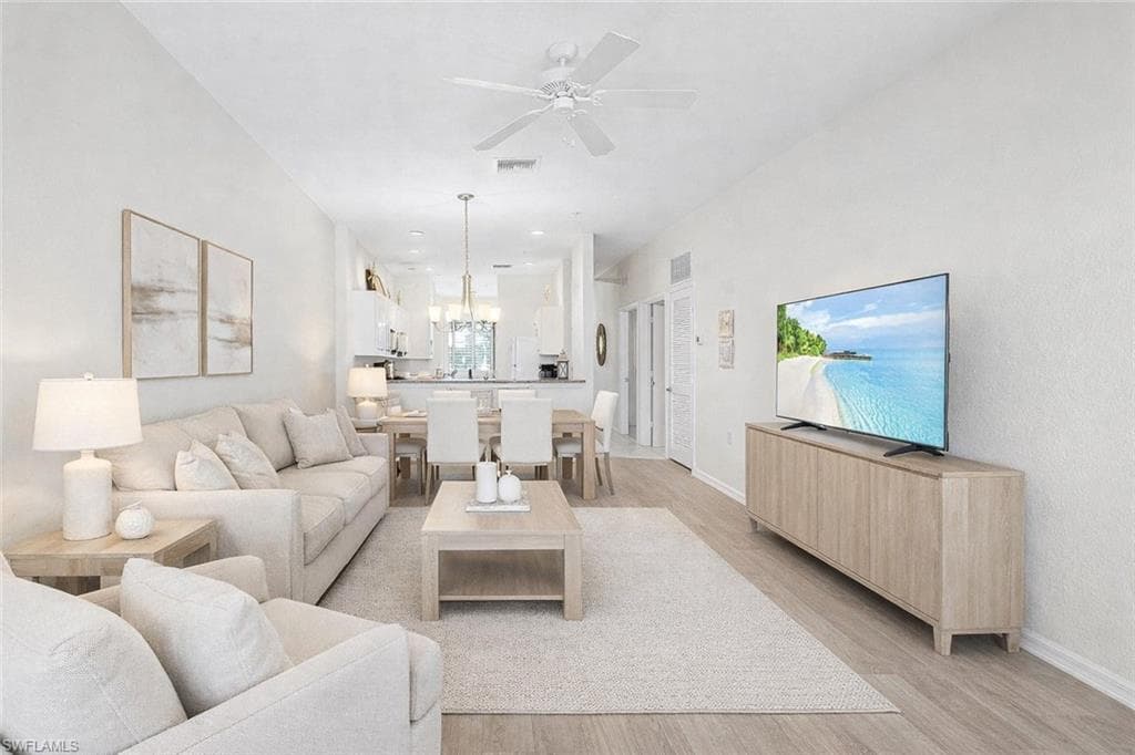 Virtual staged living area featuring a ceiling fan, light wood-style floors, and hanging lights