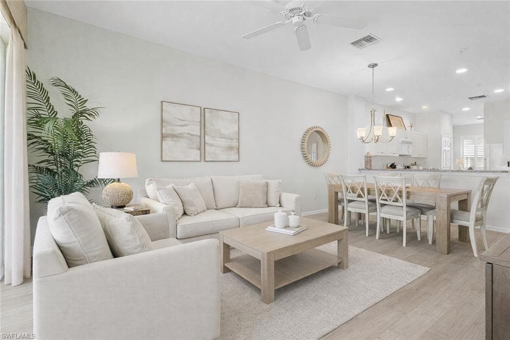 Virtual staged living area featuring a ceiling fan, light wood-style flooring, and suspended lighting