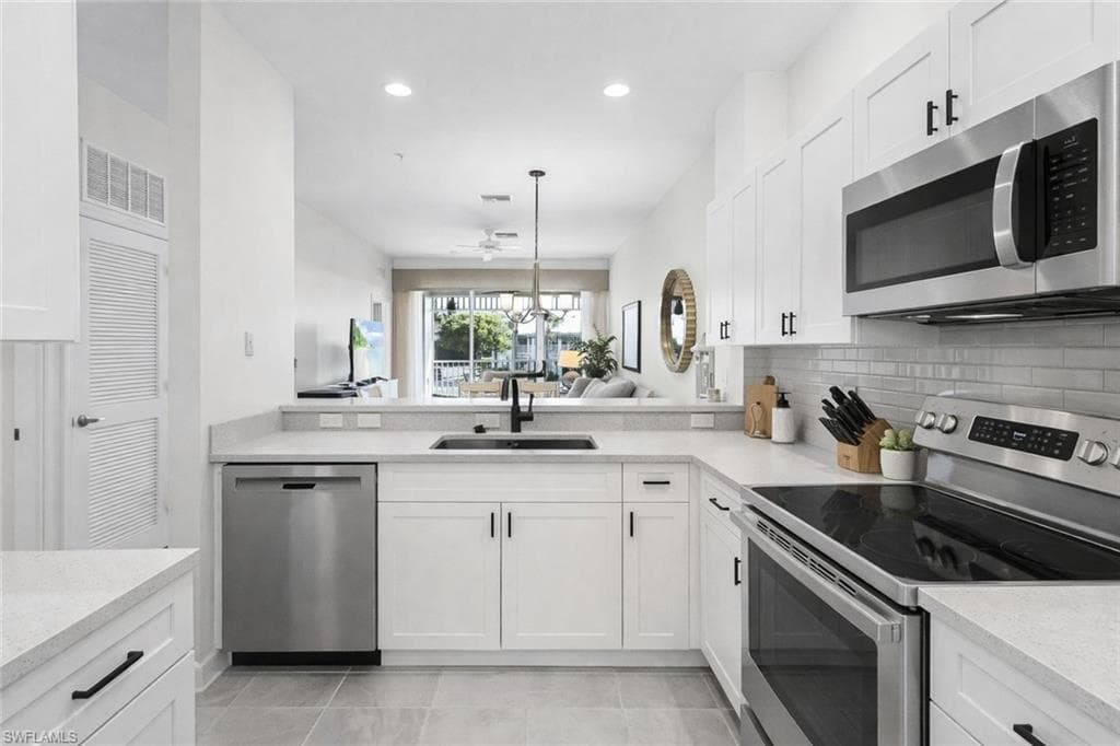 Virtual staged kitchen featuring stainless steel appliances, white cabinetry, light stone counters, and tasteful backsplash