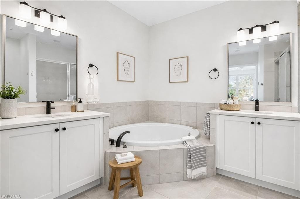 Virtual staged full bathroom featuring two vanities, a shower stall, a bath, and light tile patterned flooring