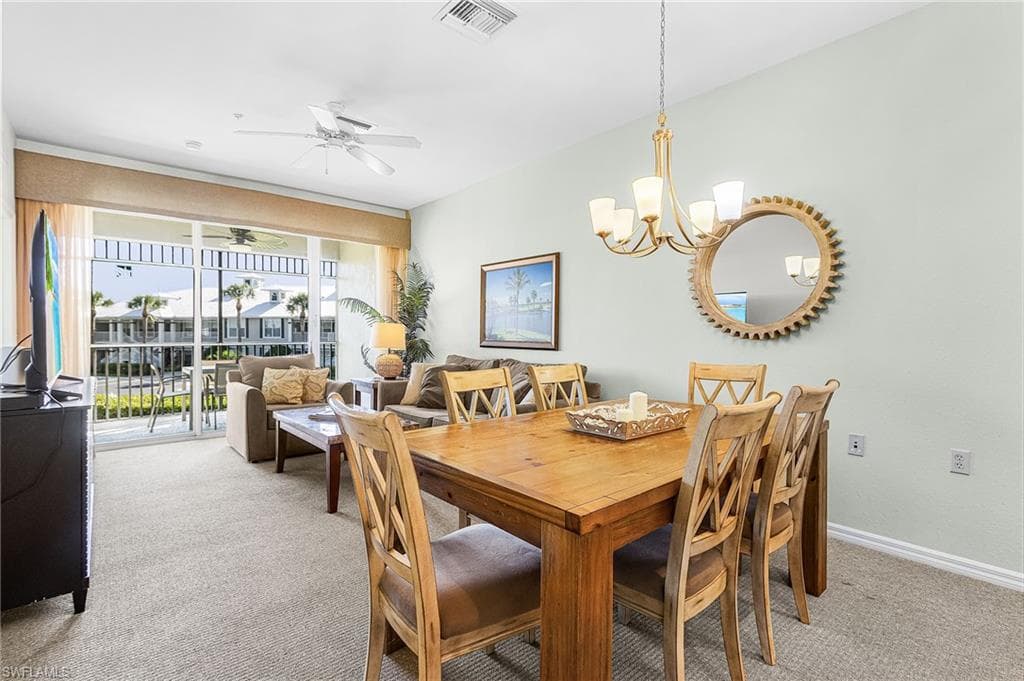 Dining room featuring light carpet, ceiling fan, and a chandelier