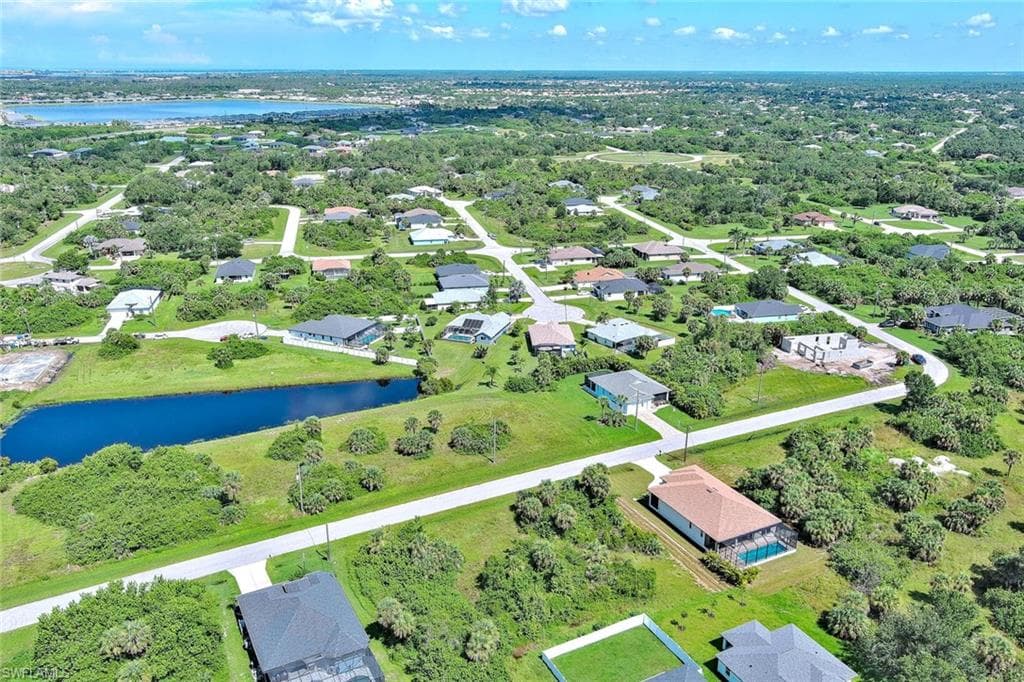 Aerial view of property and surrounding area featuring a large body of water and nearby suburban area